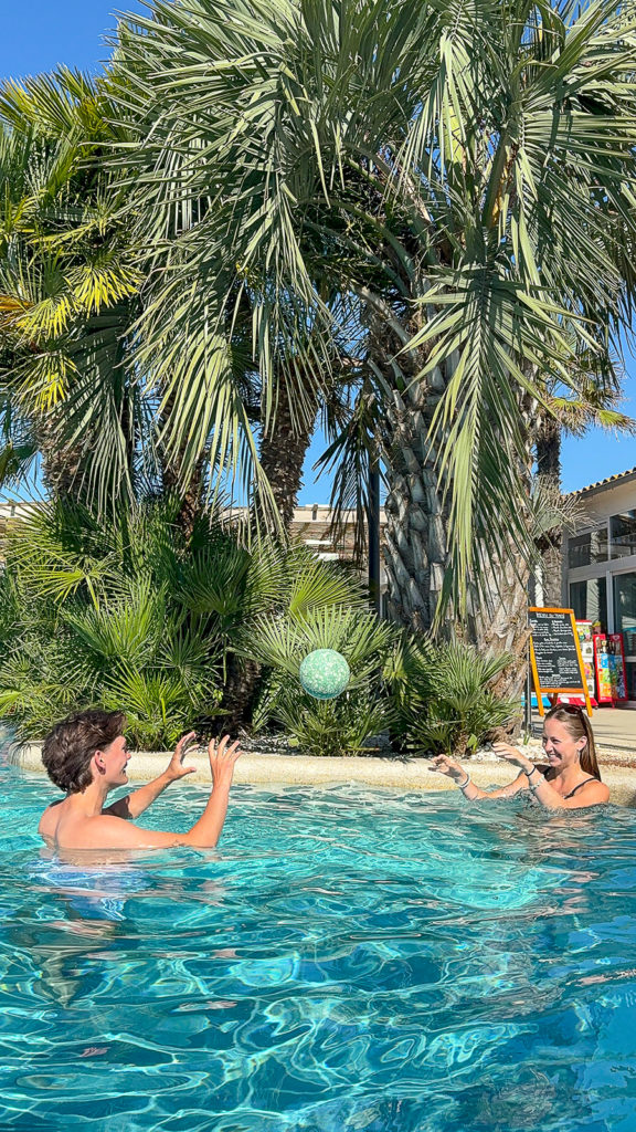 Deux personnes qui jouent avec un ballon dans une piscine